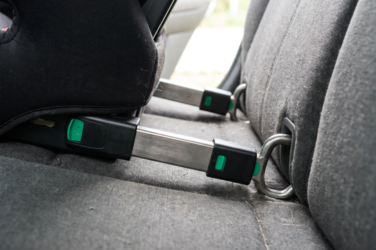 카시트 베이스의 두 ISOFIX 커넥터가 좌석 사이 앵커바에 결합되고 초록색 잠금 표시가 보이는 모습